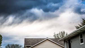 close up shot of yellow siding house over storm clouds.